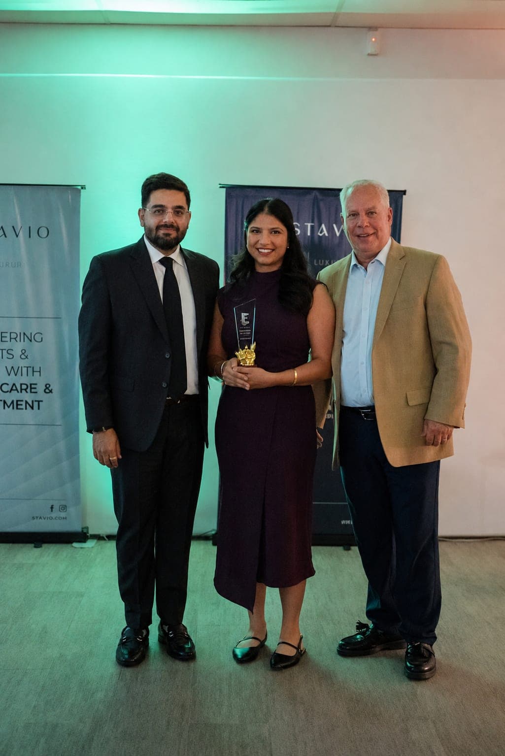 An Estavio agent holding an award between two colleagues
